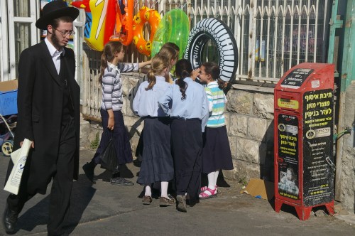 Imagen típica de una calle de Jerusalem. Un judío ortodoxo se pasea por una acera en la que juegan varias niñas con su singular atuendo